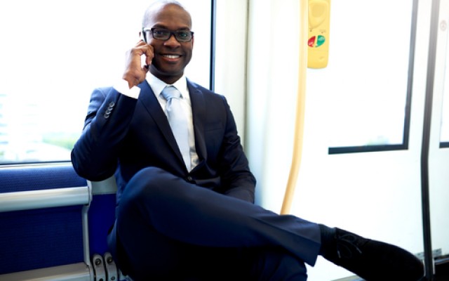 Happy Young African American Businessman Calling Someone on Mobile Phone While Commuting on a Train.