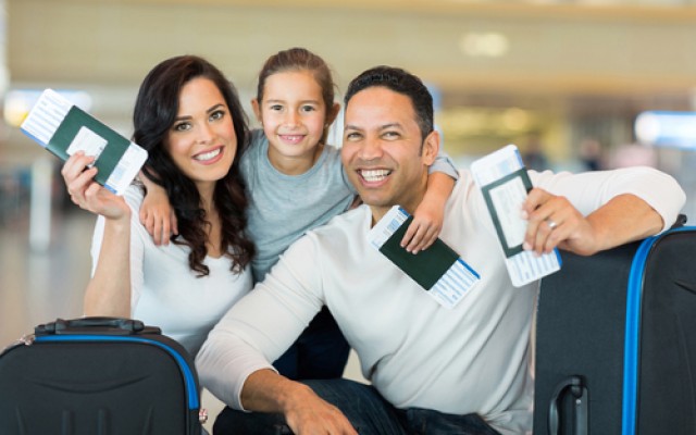 happy family holding boarding pass and passport at airport