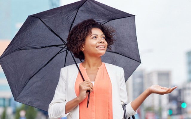 business, weather and people concept - young smiling african american businesswoman with umbrella on city street
